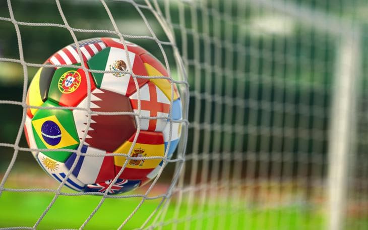 A football patterned with the flags of many nations hitting the back of a net